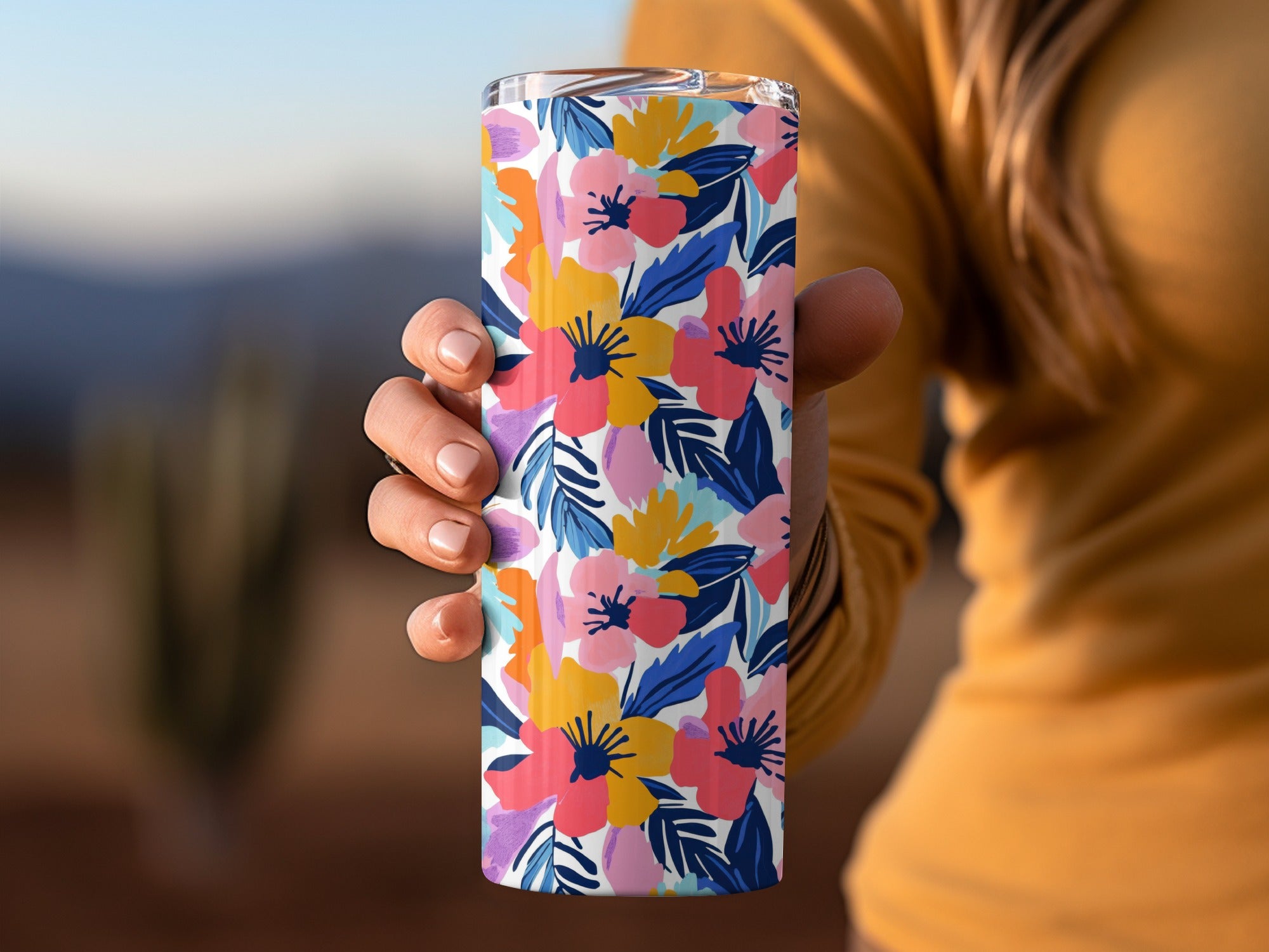 Woman holding a colorful floral patterned tumbler cup.