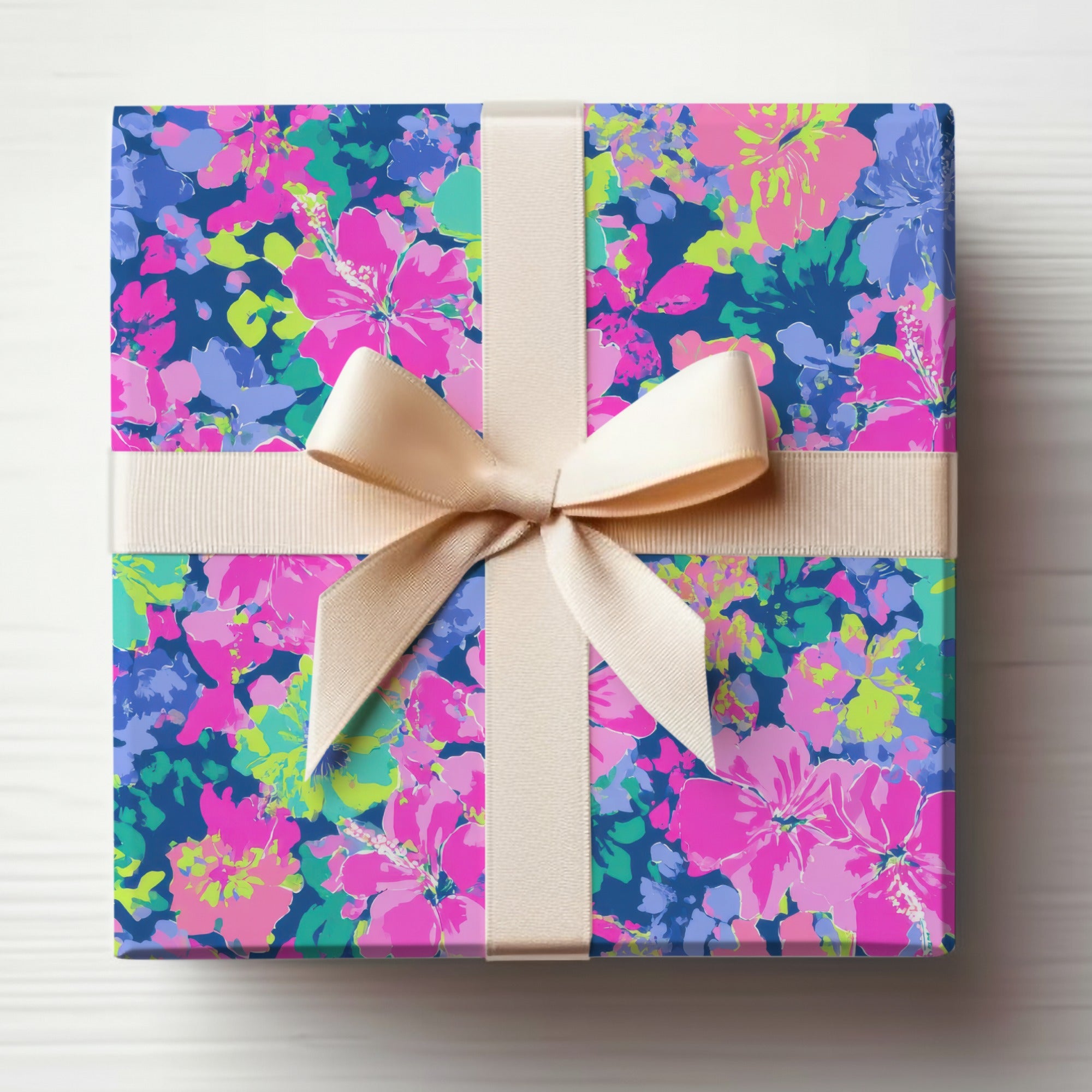 Gift box with beige ribbon and vibrant floral pattern on blue background.