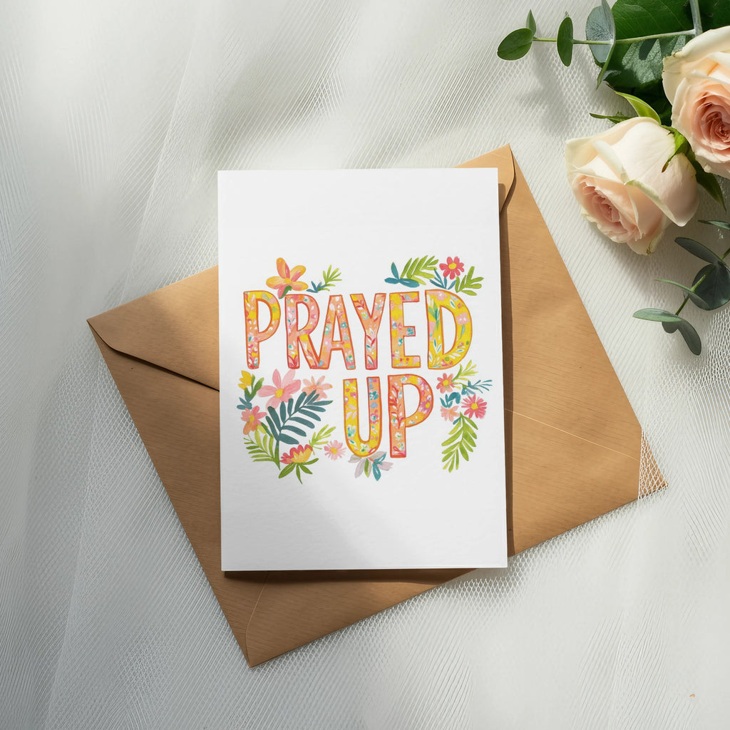Card with "Prayed Up" text and floral accents on a brown envelope.