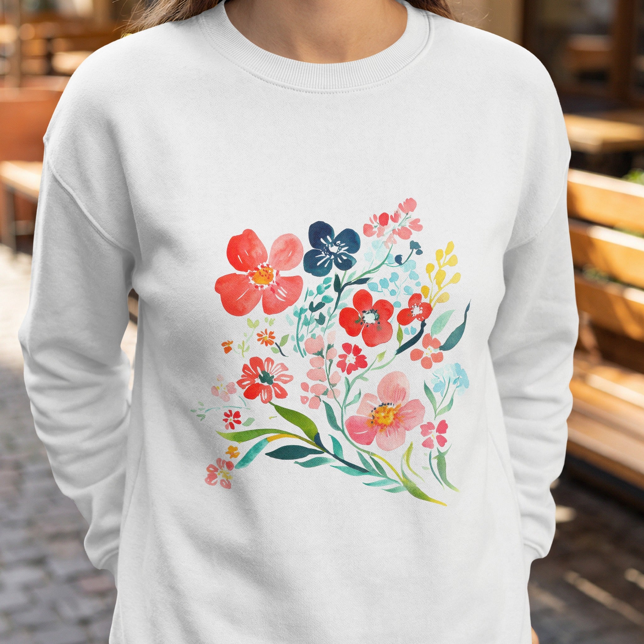 White sweatshirt with a watercolor floral bouquet in red, blue, and yellow.