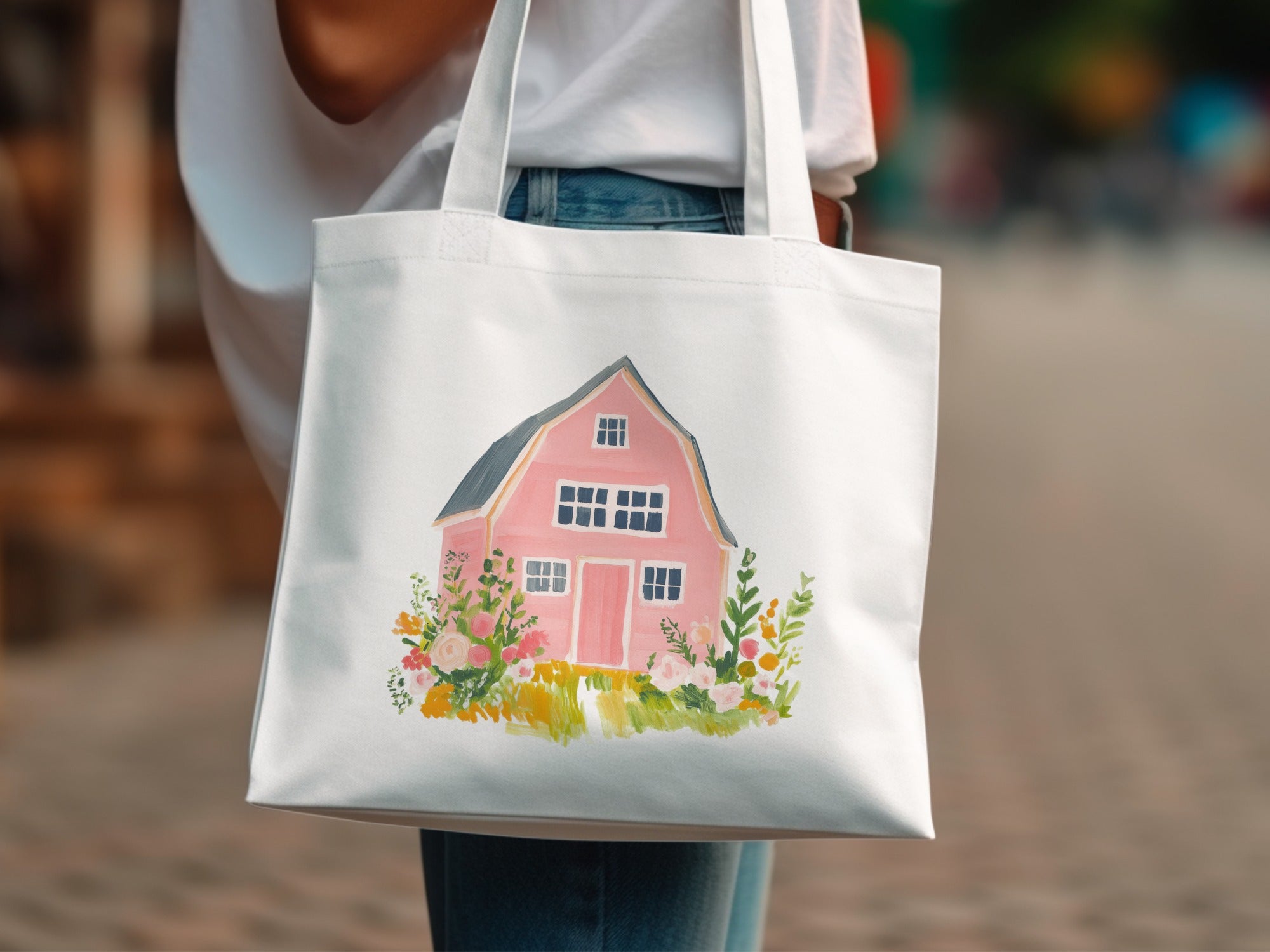 White tote bag with a watercolor illustration of a pink barn and floral accents.