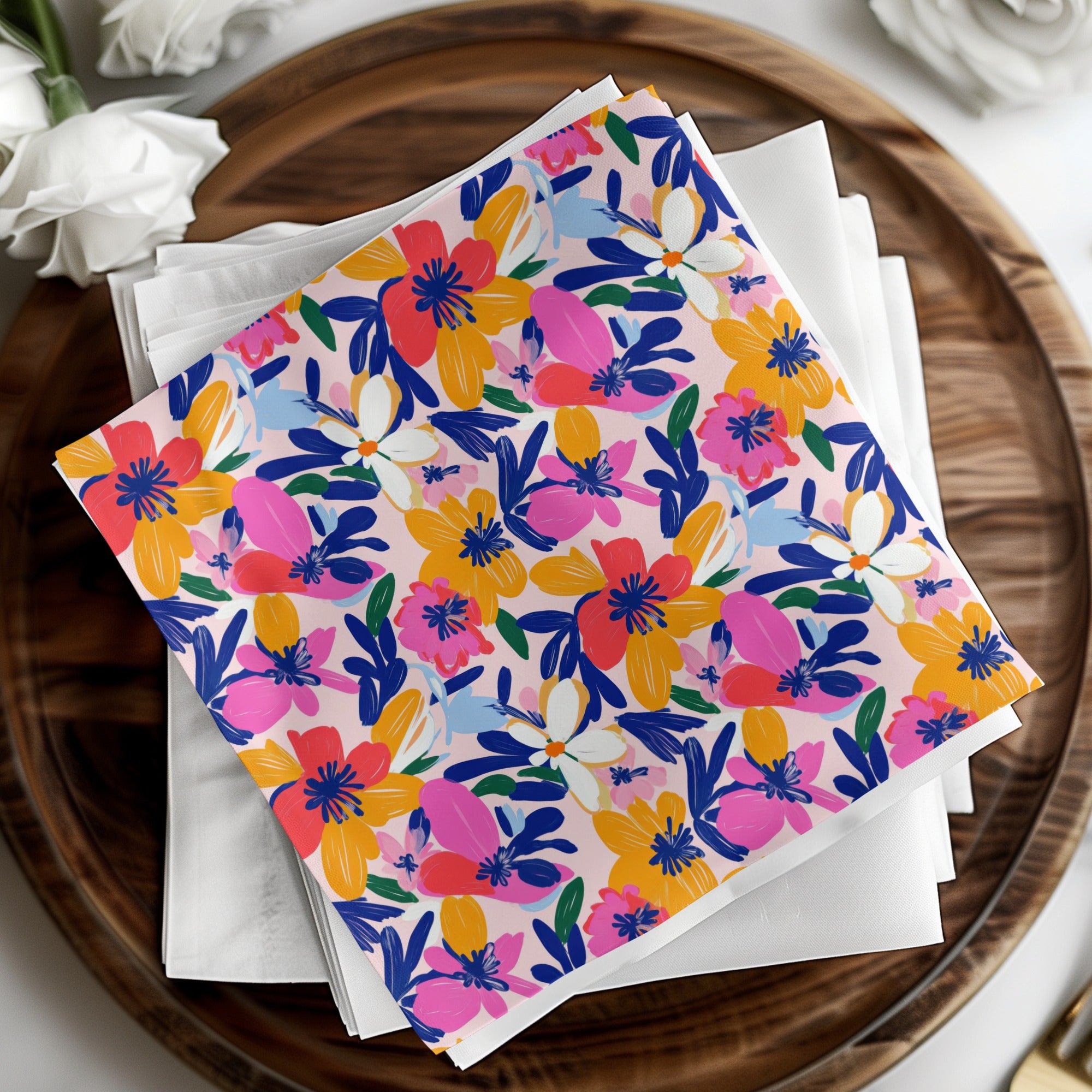 Colorful floral patterned napkins on a wooden tray with white napkins.