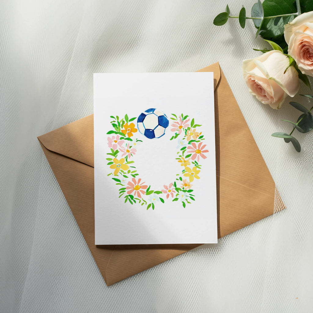 Card with floral wreath and soccer ball, on brown envelope.
