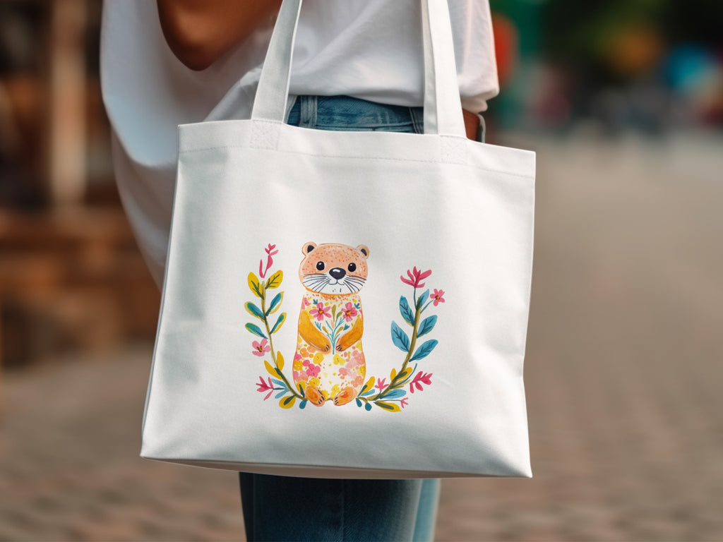 White tote bag with a watercolor otter illustration and floral wreath.