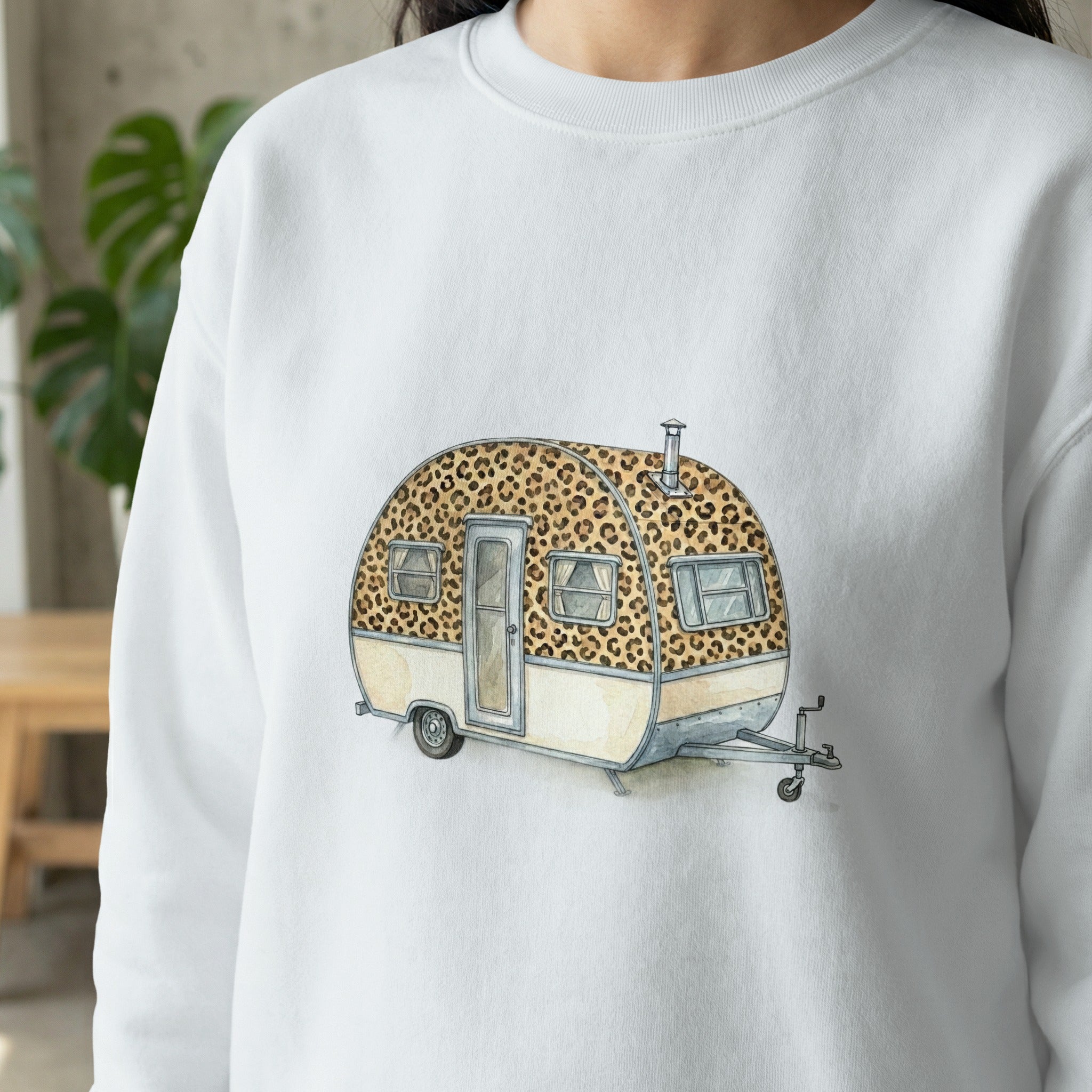 White sweatshirt with a watercolor illustration of a leopard print travel trailer.