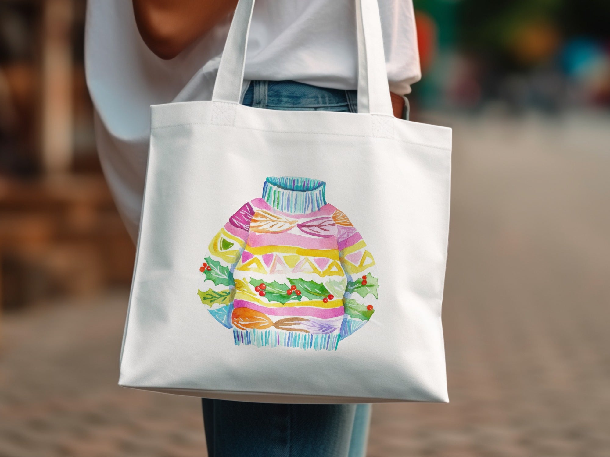 White tote bag with colorful festive sweater illustration and holly berries.