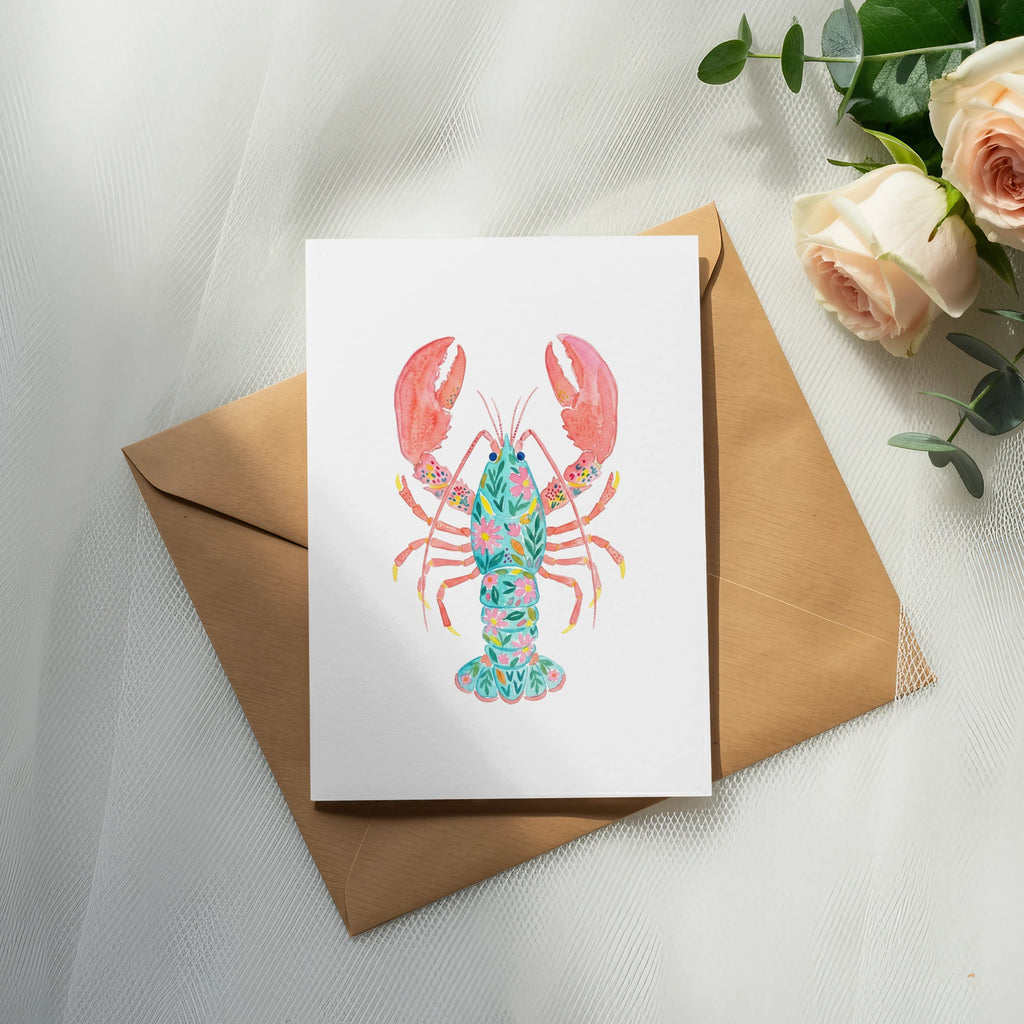 Watercolor lobster illustration on a card, resting on a brown envelope.