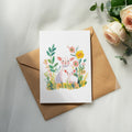 Watercolor illustration of a mother sheep and lamb with flowers on a card.
