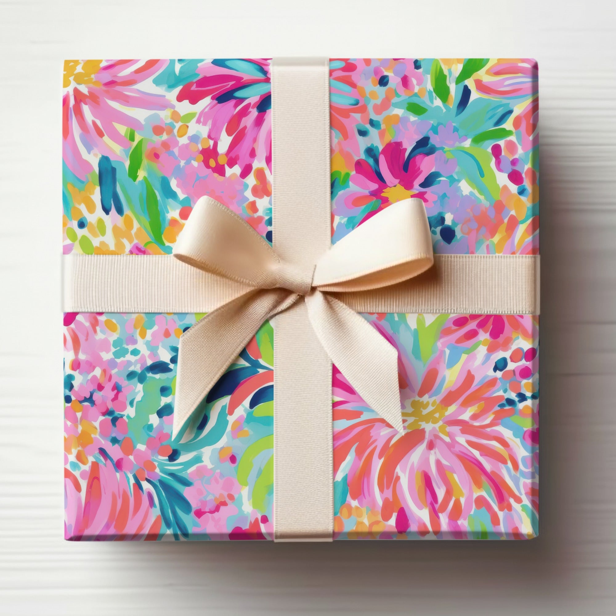 Gift box wrapped in bright floral paper tied with a cream ribbon.