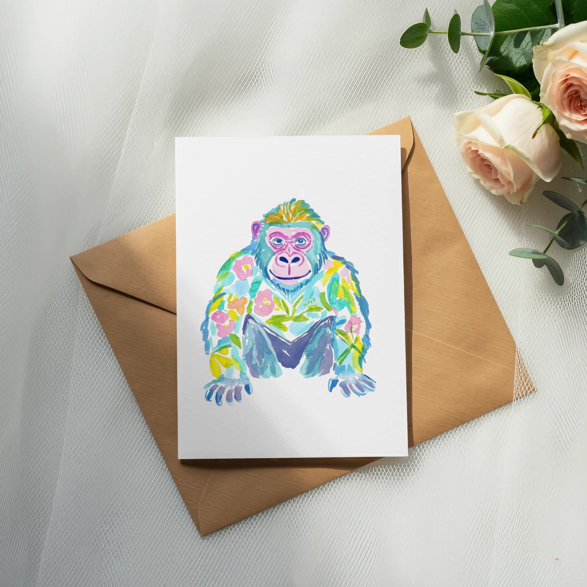 Watercolor gorilla illustration on a card with floral accents, on brown envelope.