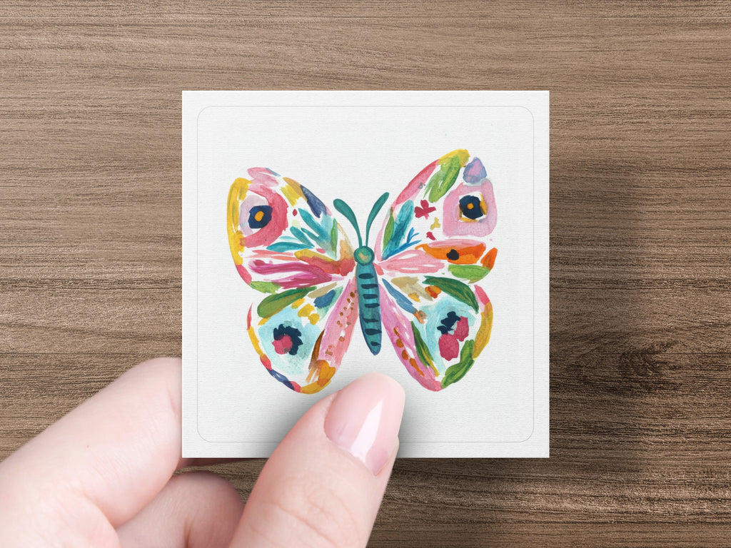 Colorful butterfly illustration on a white card held by a hand.