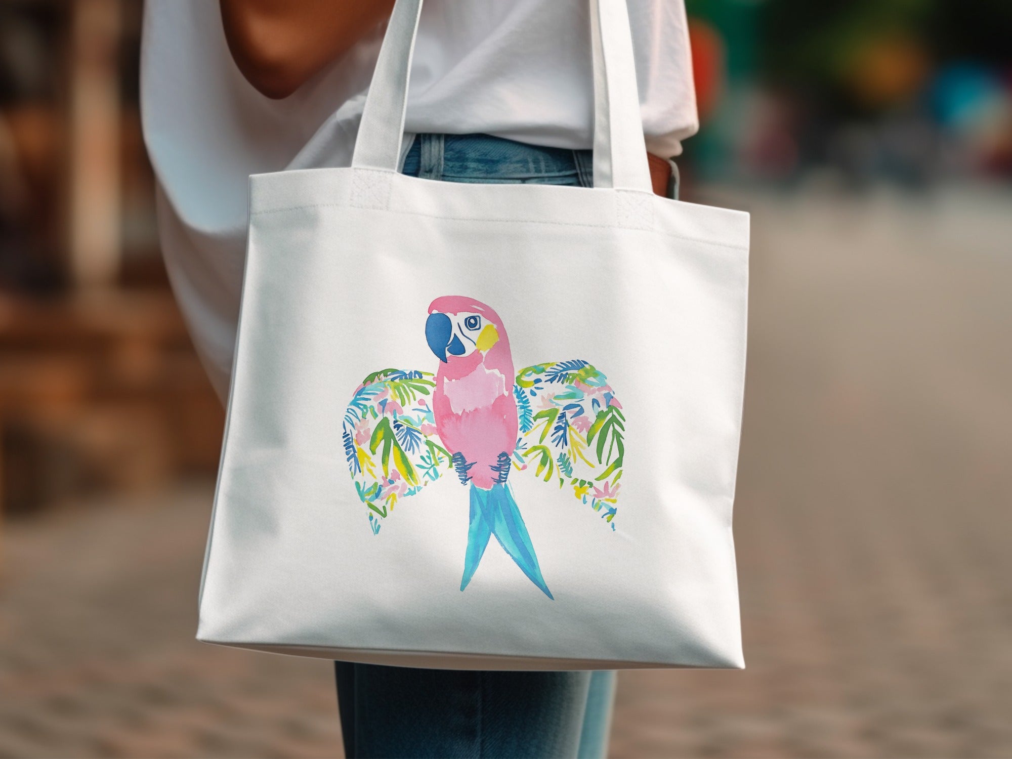 White tote bag with a colorful macaw and tropical leaf design.