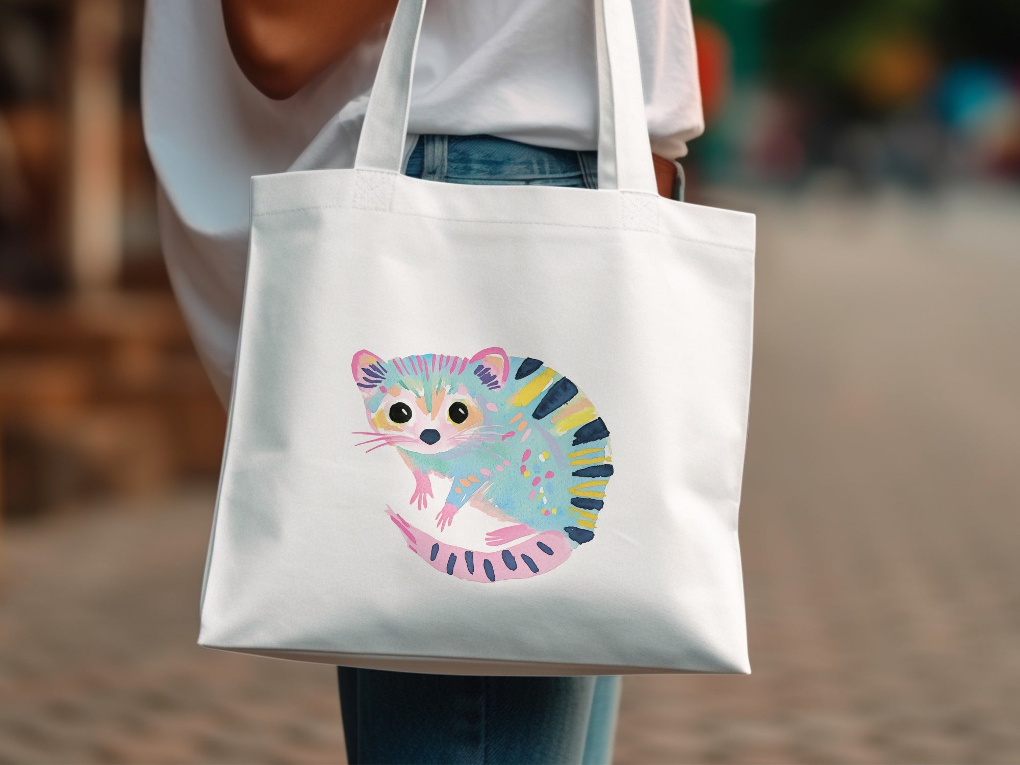 White tote bag with a colorful, stylized raccoon illustration.