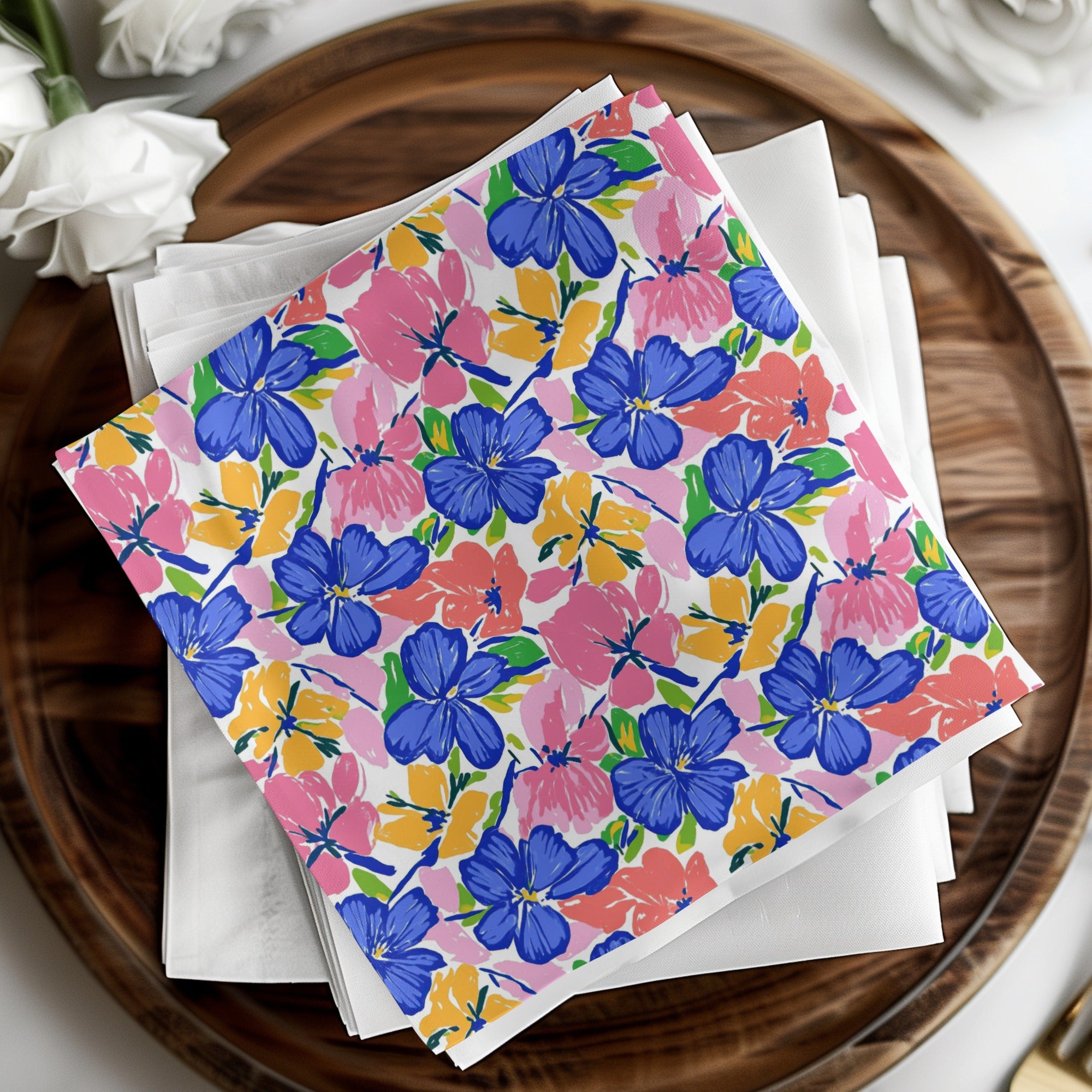 Colorful floral pattern napkins on a wooden tray with white napkins.
