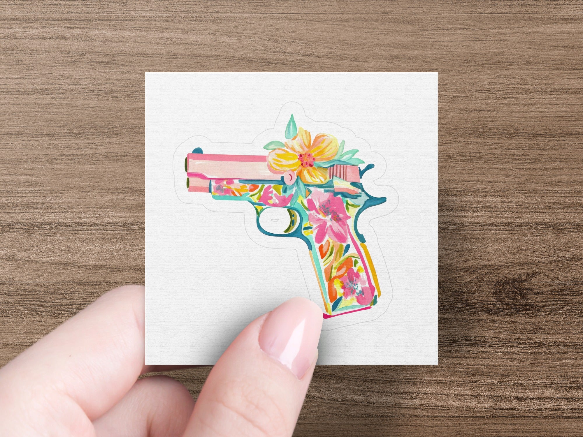 Pistol decorated with colorful floral pattern, held by a hand.