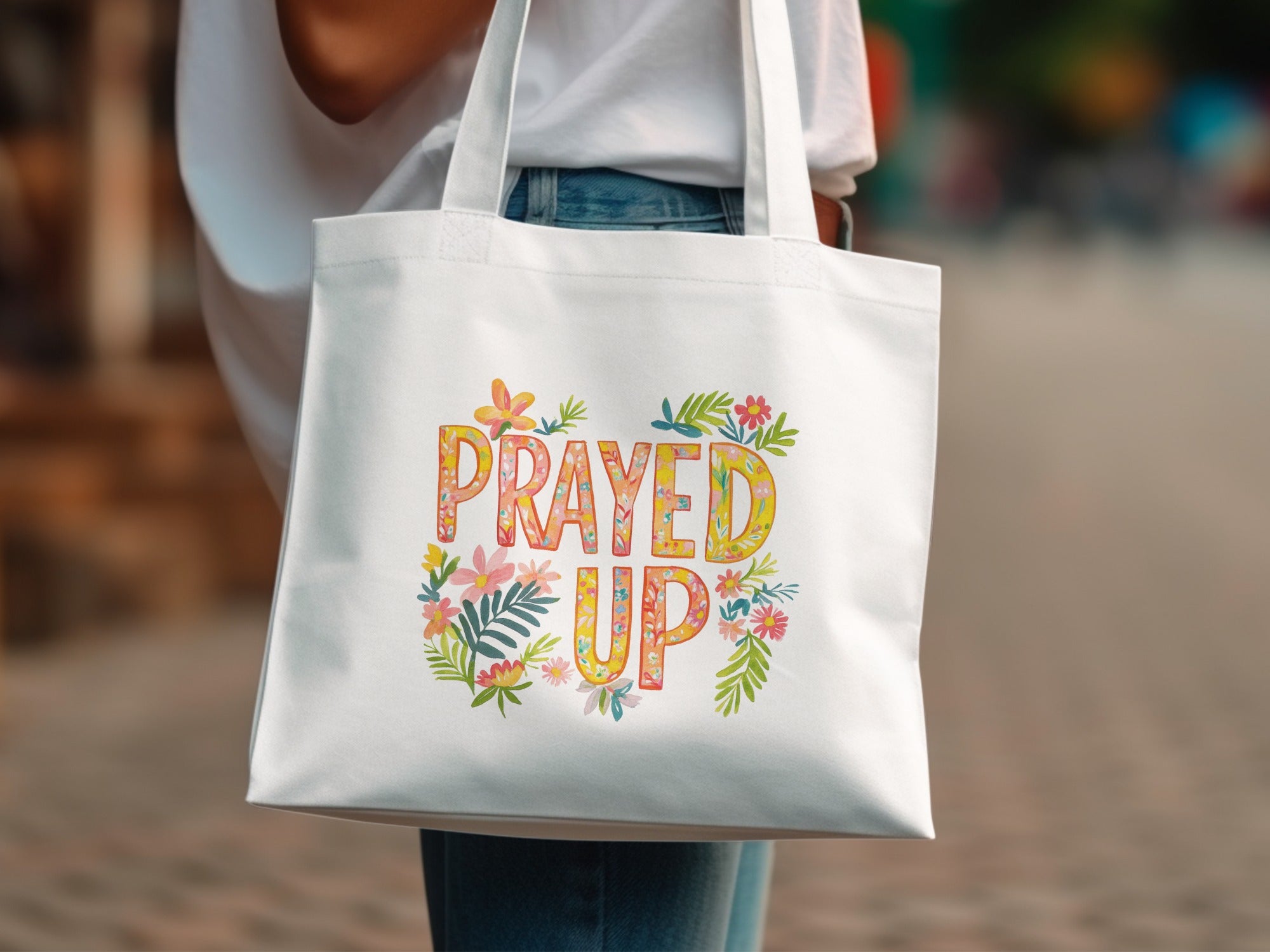 White tote bag with "Prayed Up" text surrounded by colorful floral accents.