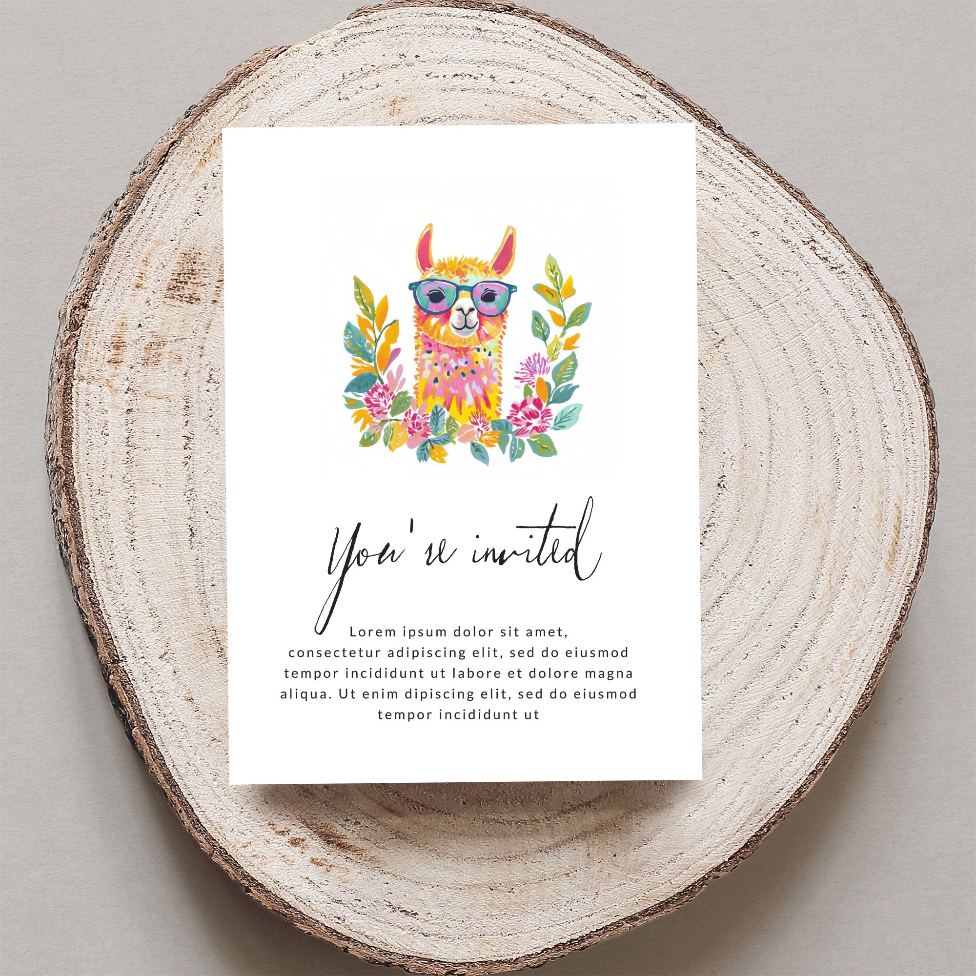 Card with illustrated llama and "You're invited" text on wood slice.