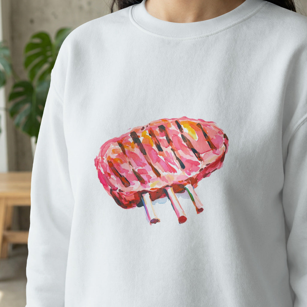 Watercolor illustration of grilled lamb chops on a white sweatshirt.