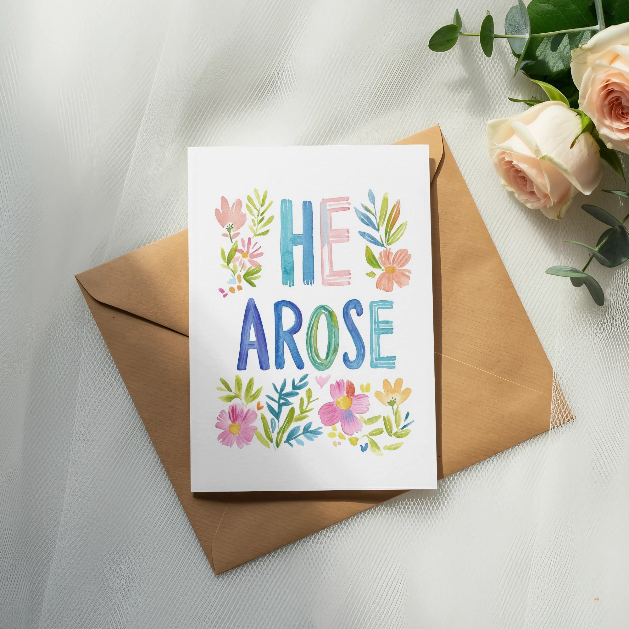 Watercolor greeting card with "HE AROSE" and floral design on an envelope.