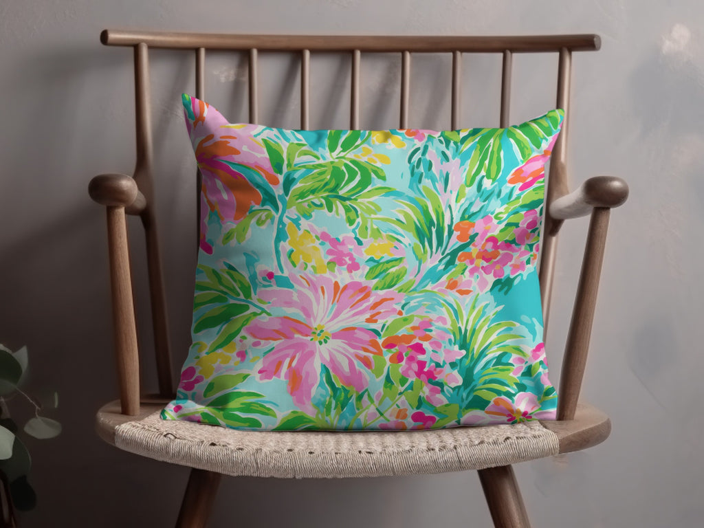 Bright floral throw pillow with pink, coral, and green blossoms on turquoise background.