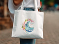 White canvas tote bag with a watercolor wave and floral design.