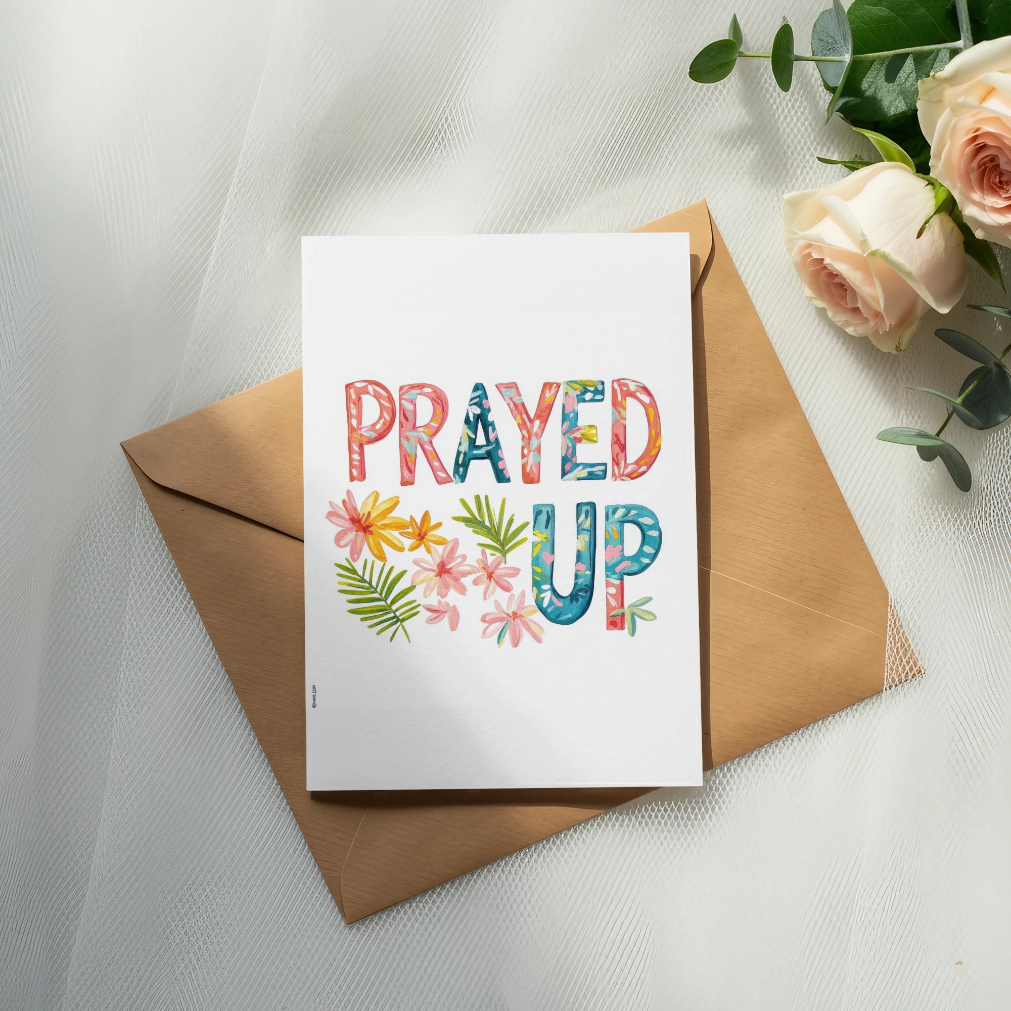 Greeting card with "PRAYED UP" text and floral accents on a brown envelope.