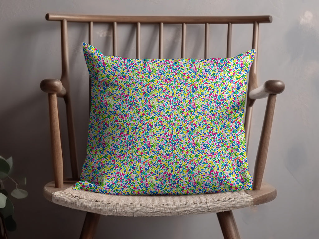 Colorful abstract floral print throw pillow on a wooden chair.