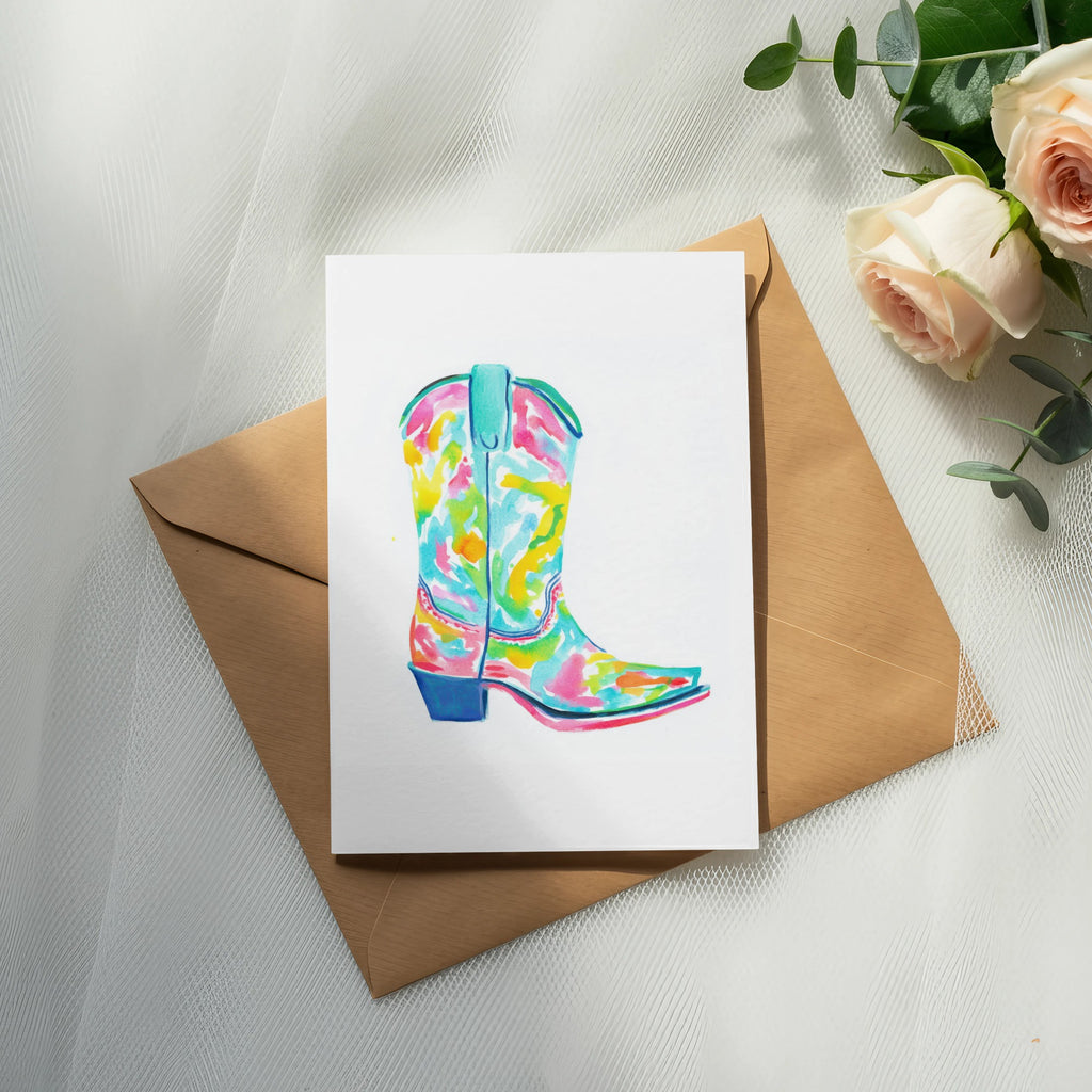 Colorful watercolor cowboy boot illustration on a white card with envelope and flowers.