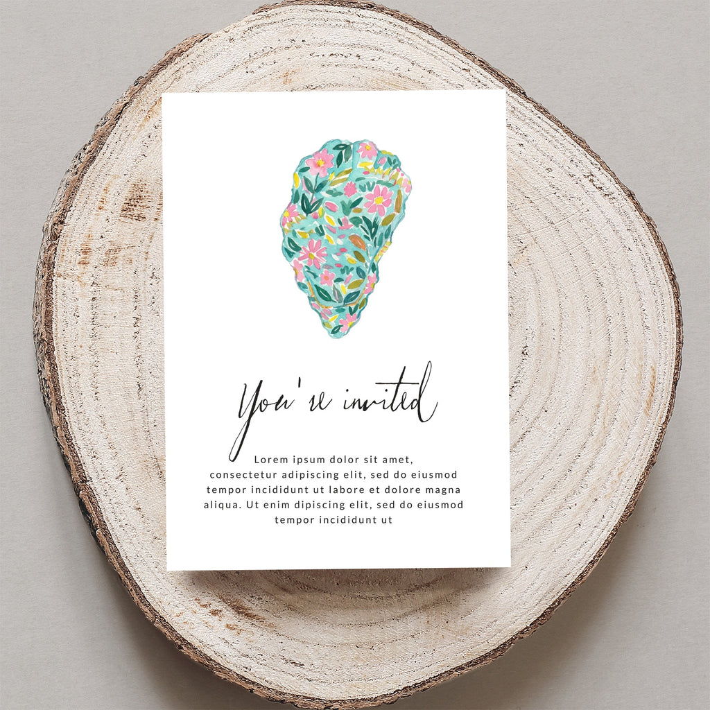 Invitation card with "You're invited" text and floral design on wood slice.