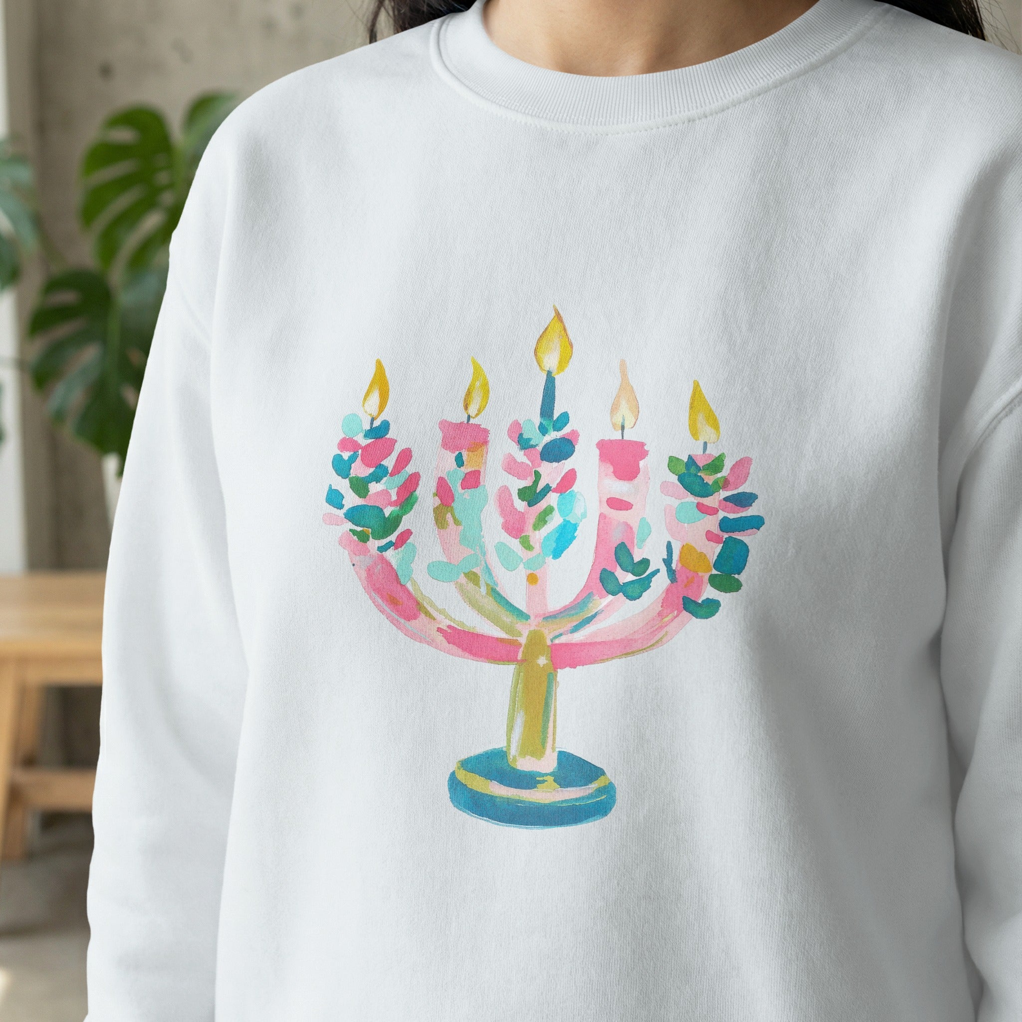 Watercolor menorah with colorful candles on a white sweatshirt.