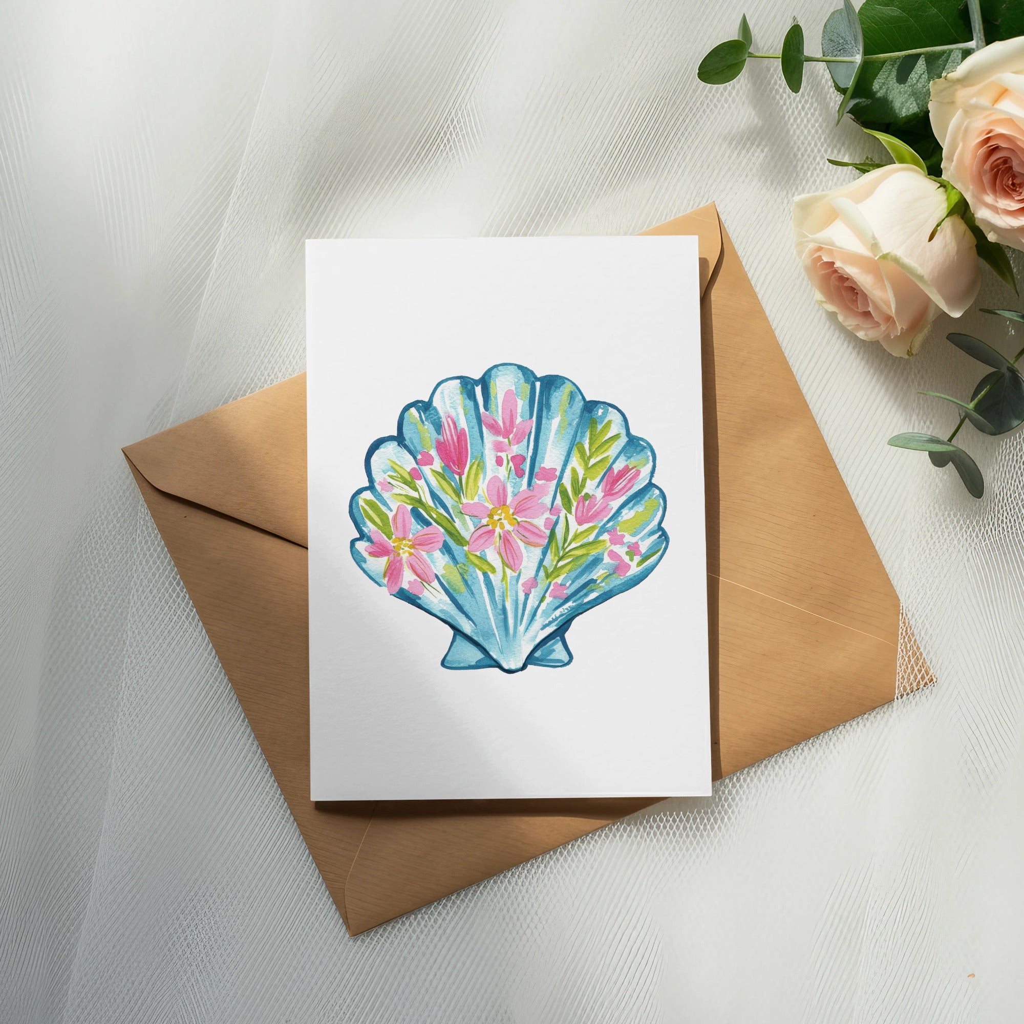 Watercolor illustration of a blue seashell filled with pink and green flowers on white card.