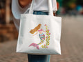 White tote bag featuring a watercolor illustration of a mermaid with pink flowers.