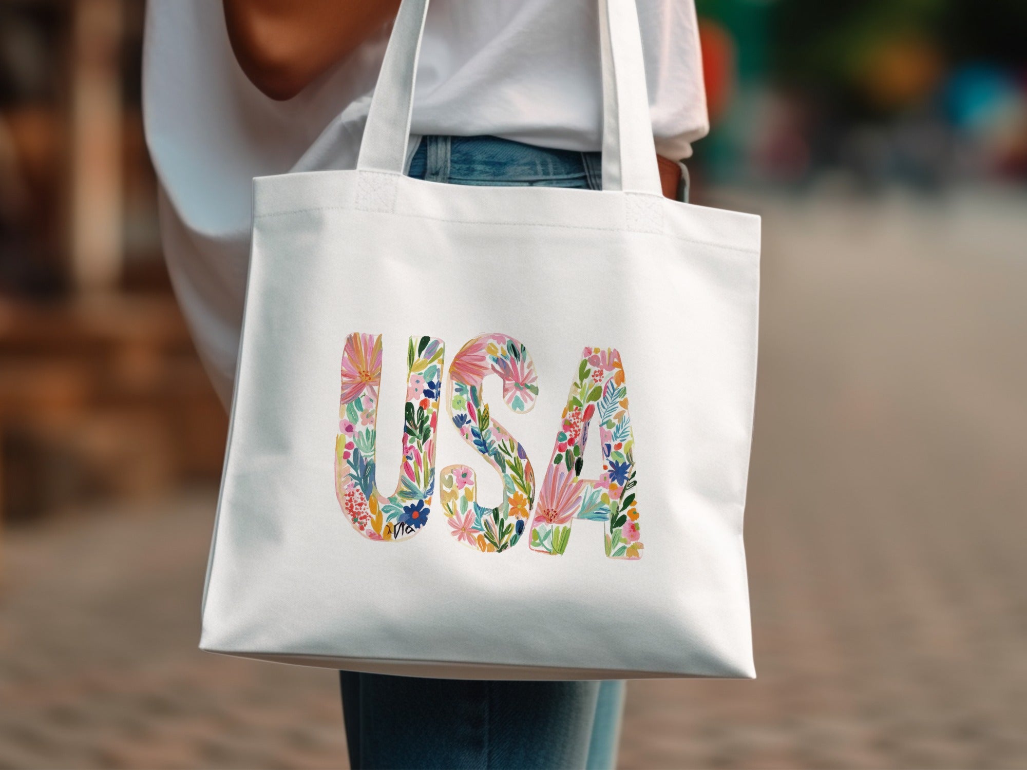 White tote bag with "USA" spelled out in colorful floral letters.