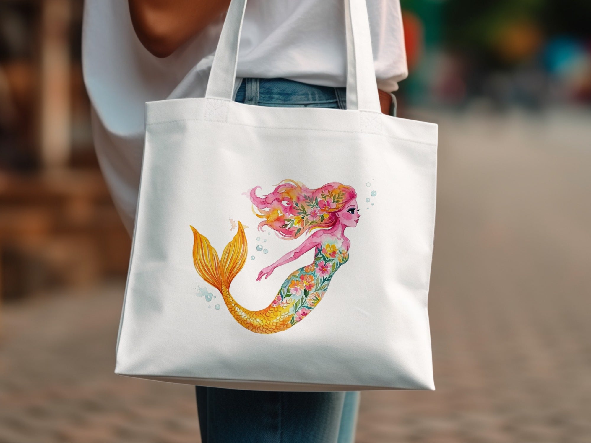 White tote bag with a watercolor mermaid illustration featuring floral accents and bubbles.