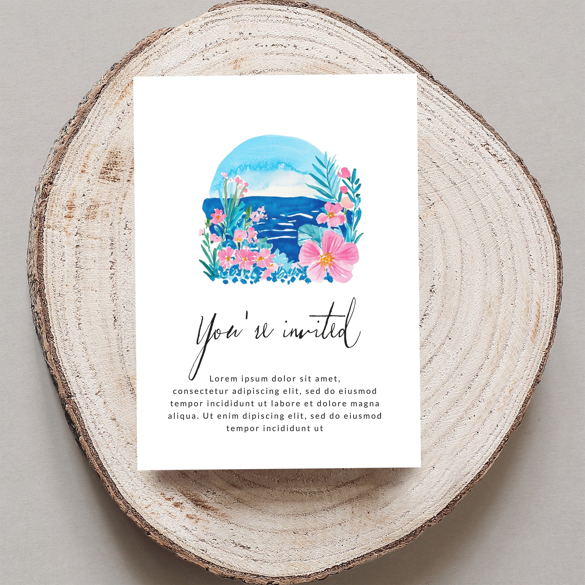 Invitation card with "You're invited" and floral artwork on a wood slice.