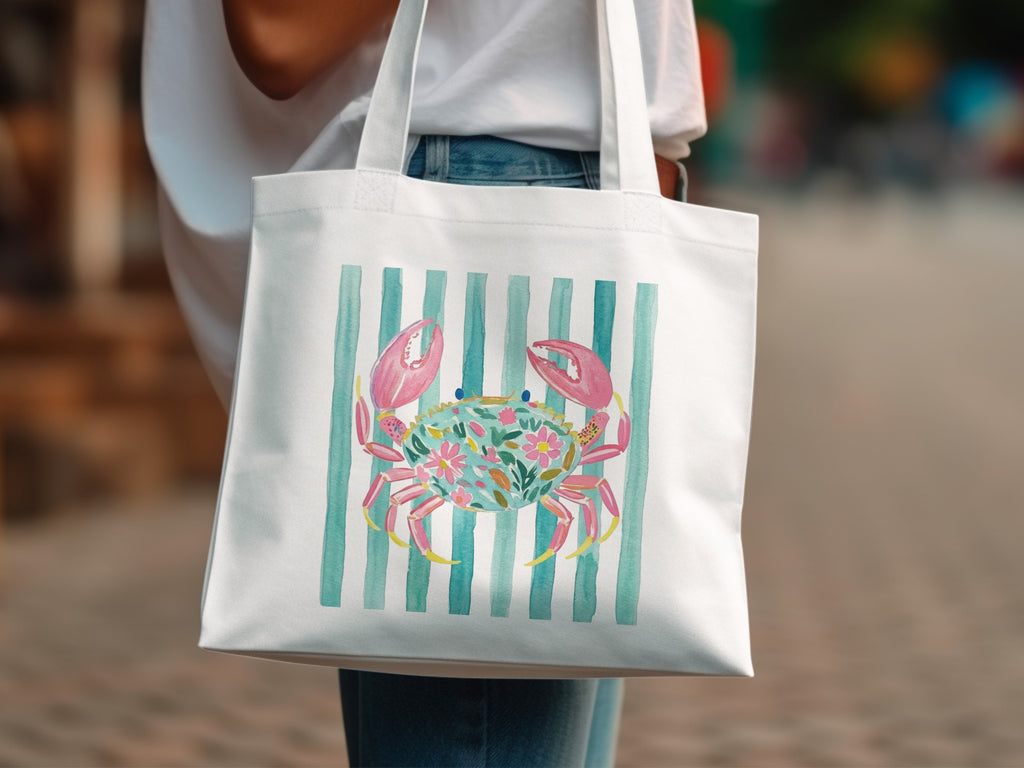 White tote bag with a crab design featuring colorful floral accents on a striped background.