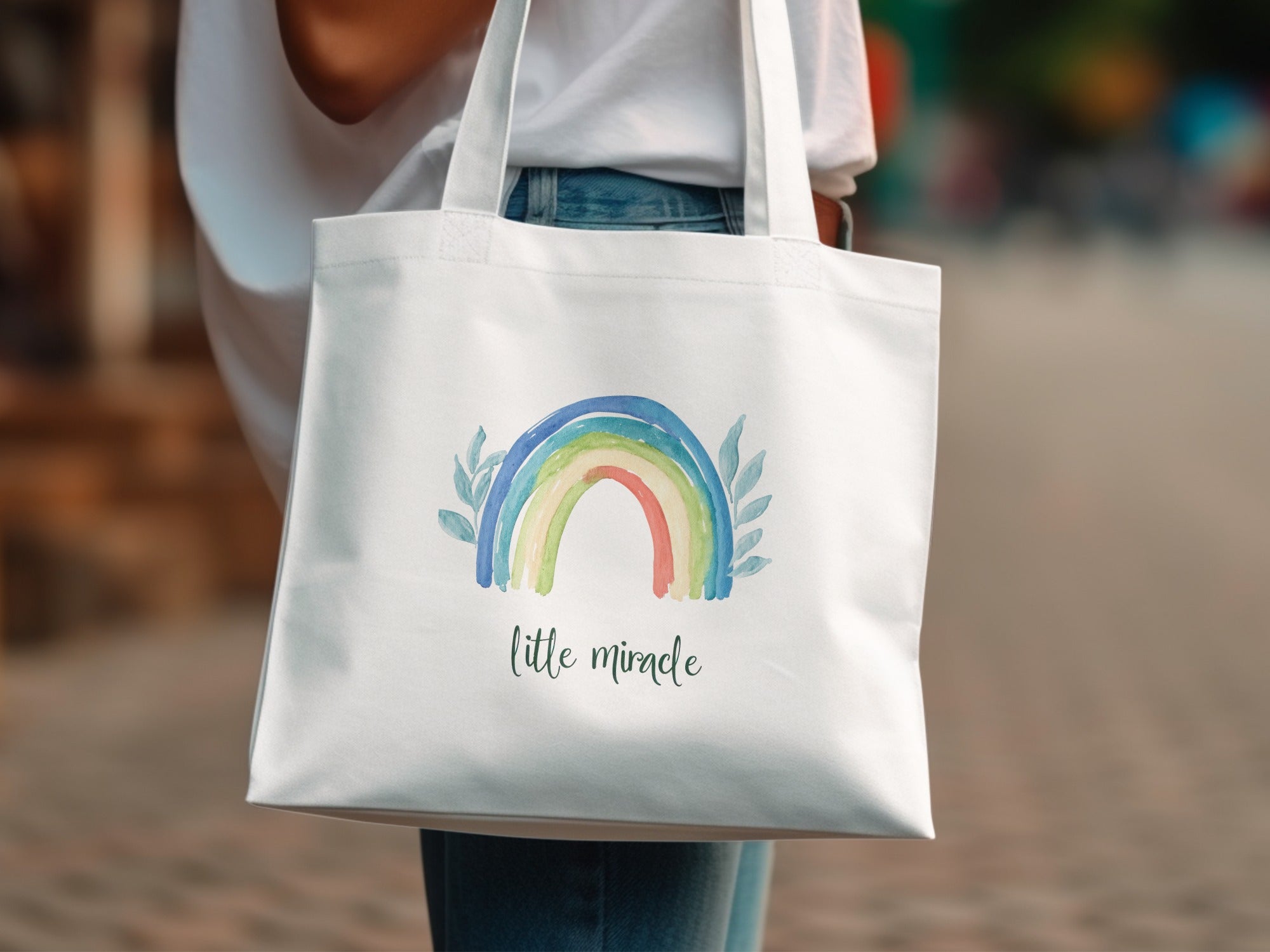 White tote bag with rainbow and "little miracle" text.