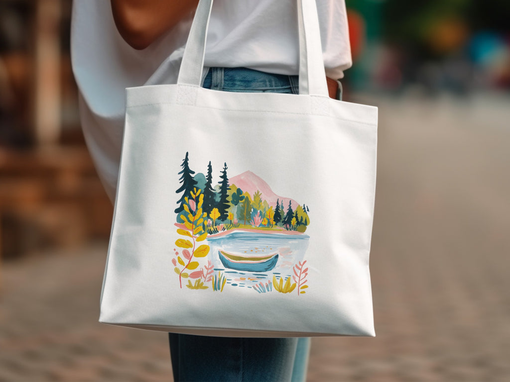 White canvas tote bag with a watercolor landscape of a lake, trees, and mountains.
