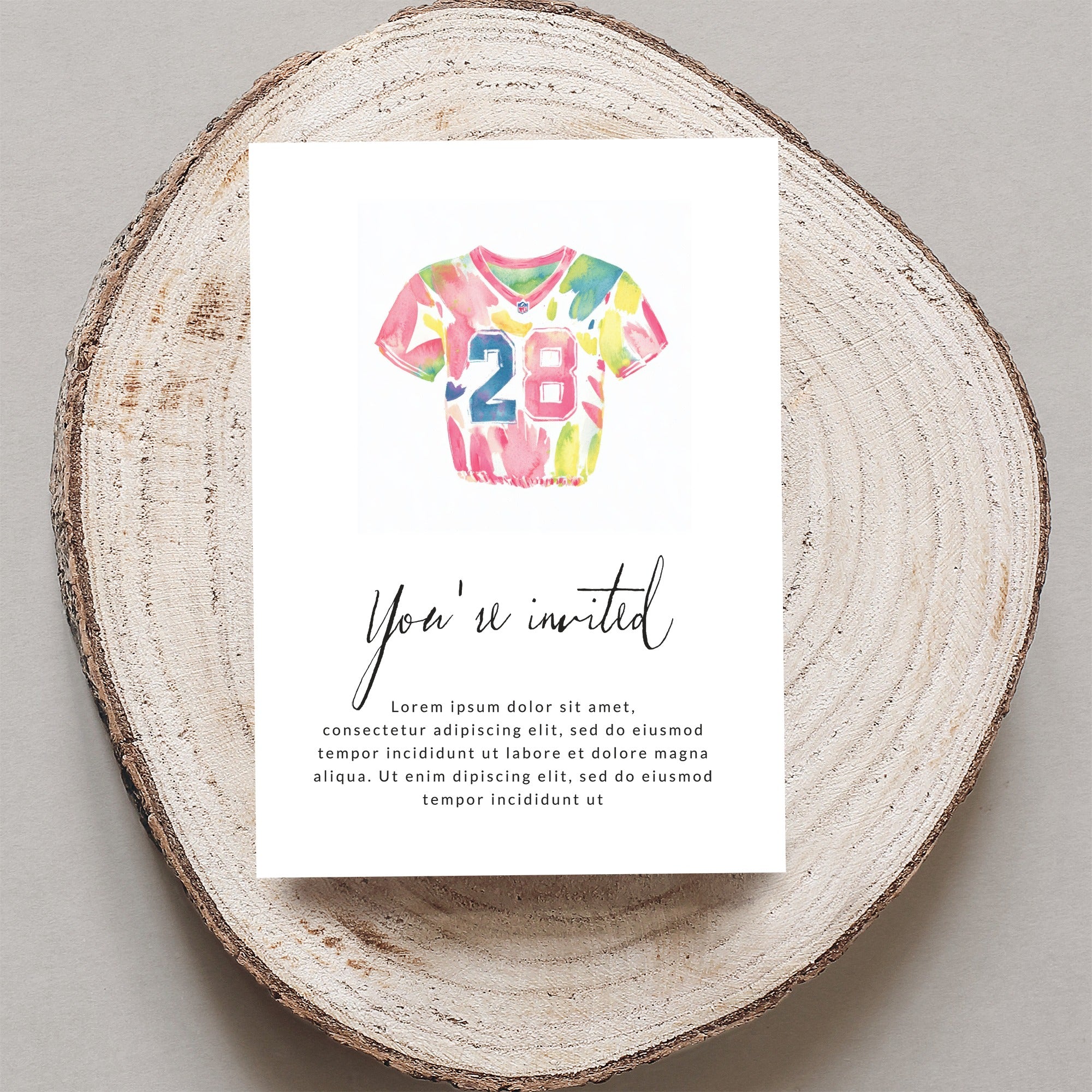 Watercolor jersey with "28" and "You're invited" text on a wood slice.