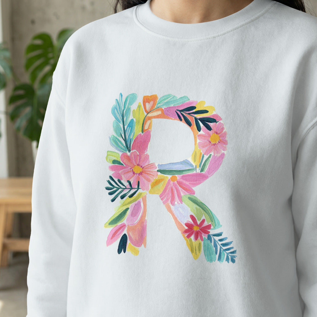 White sweatshirt with a large, colorful floral letter R.