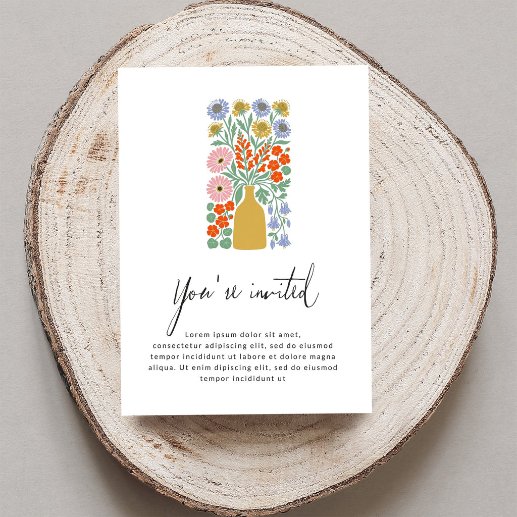 Invitation card with "You're invited" and floral illustration on wood slice.