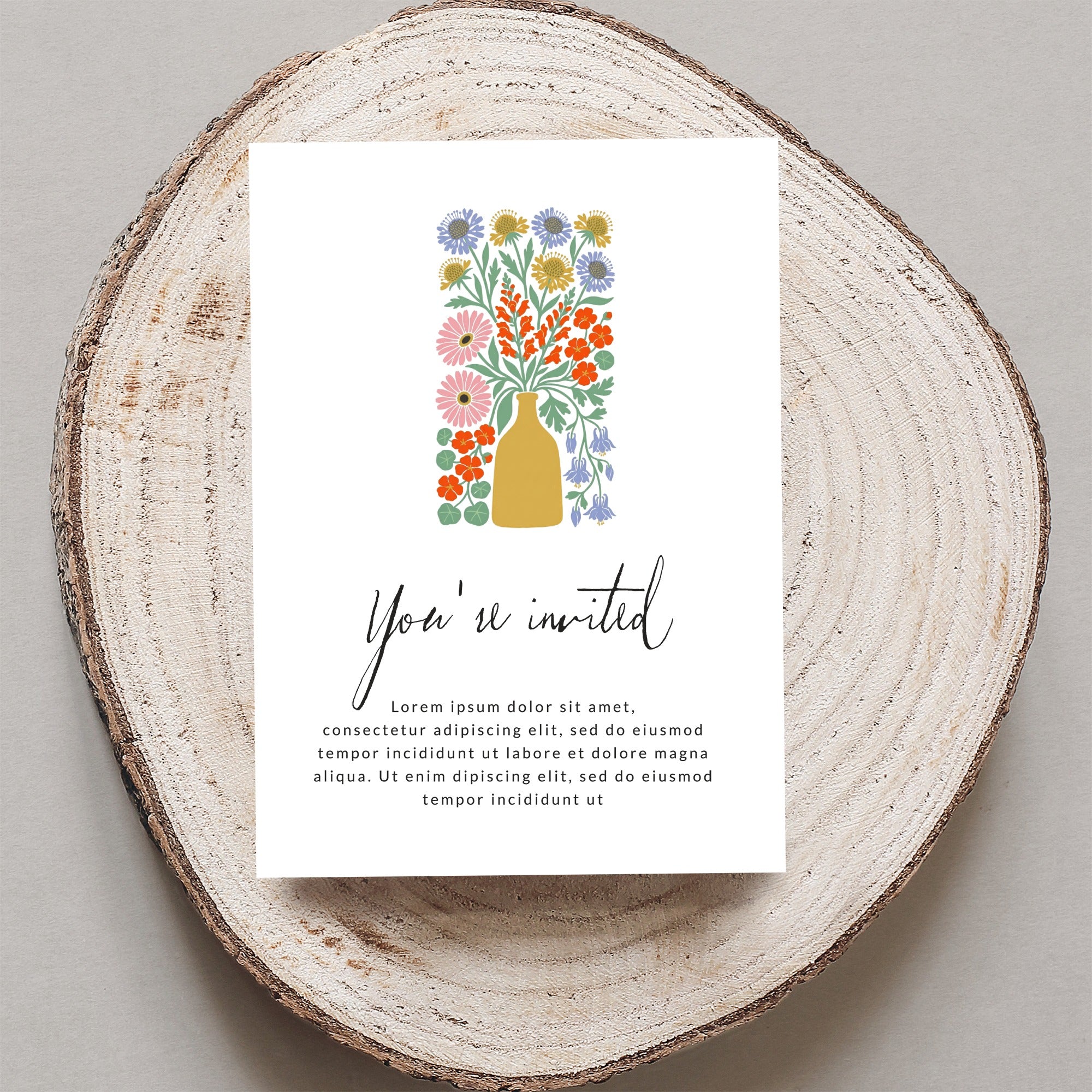 Invitation card with "You're invited" and floral illustration on wood slice.