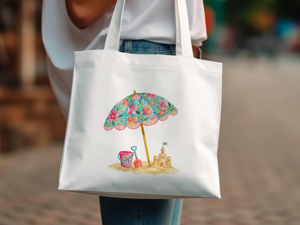 White tote bag with a beach scene illustration featuring a sandcastle and umbrella.