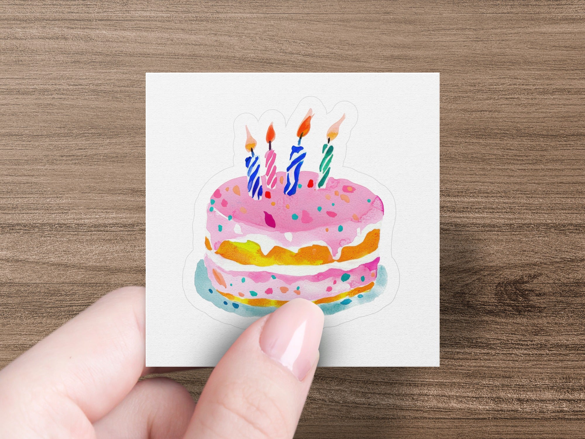 Pink frosted birthday cake with four colorful candles on a card held by a hand.