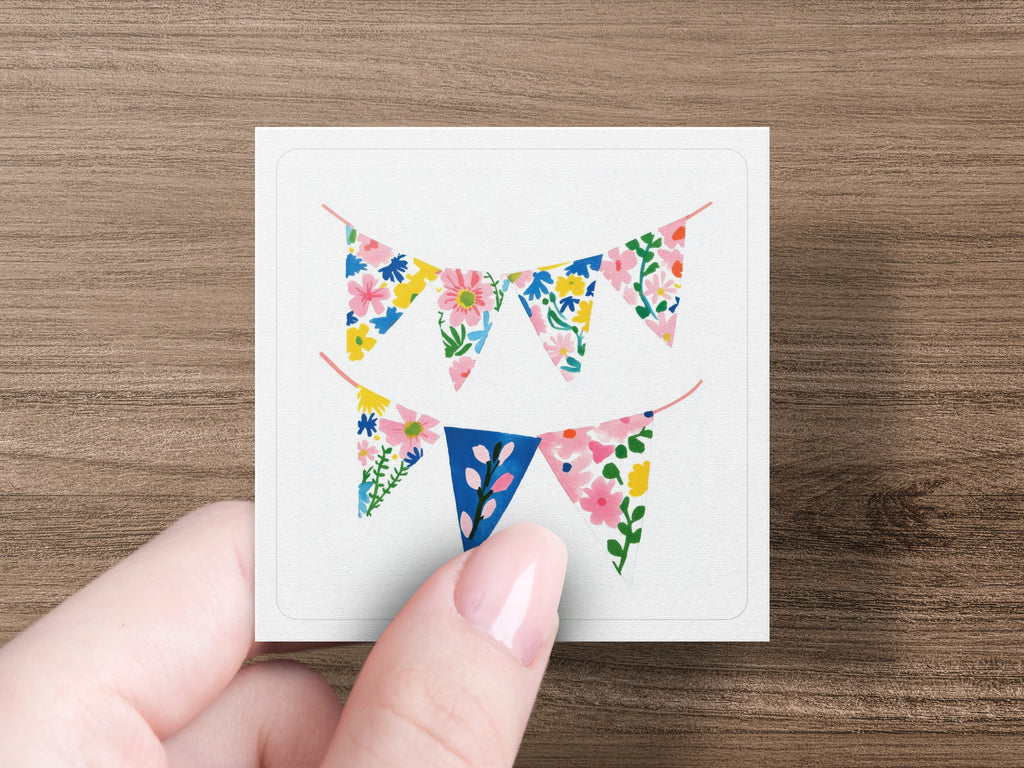 Floral bunting flags on string, held by a hand.