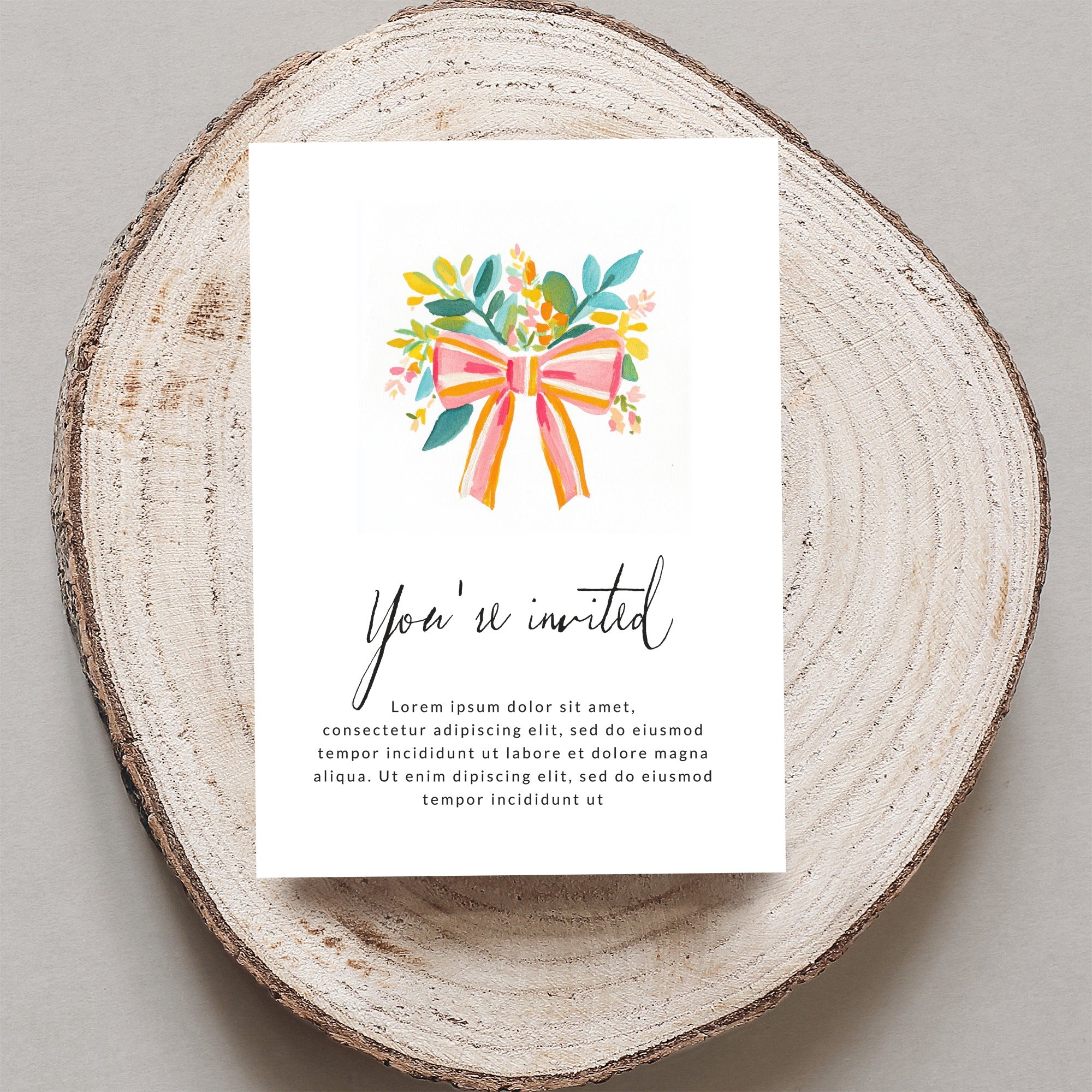 Invitation card with "You're invited" and placeholder text on wood slice.