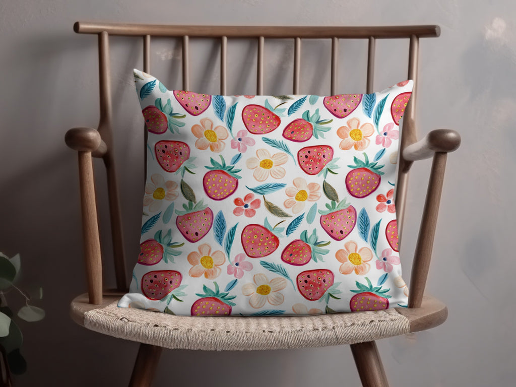 Throw pillow with a strawberry and floral pattern on a wooden chair.