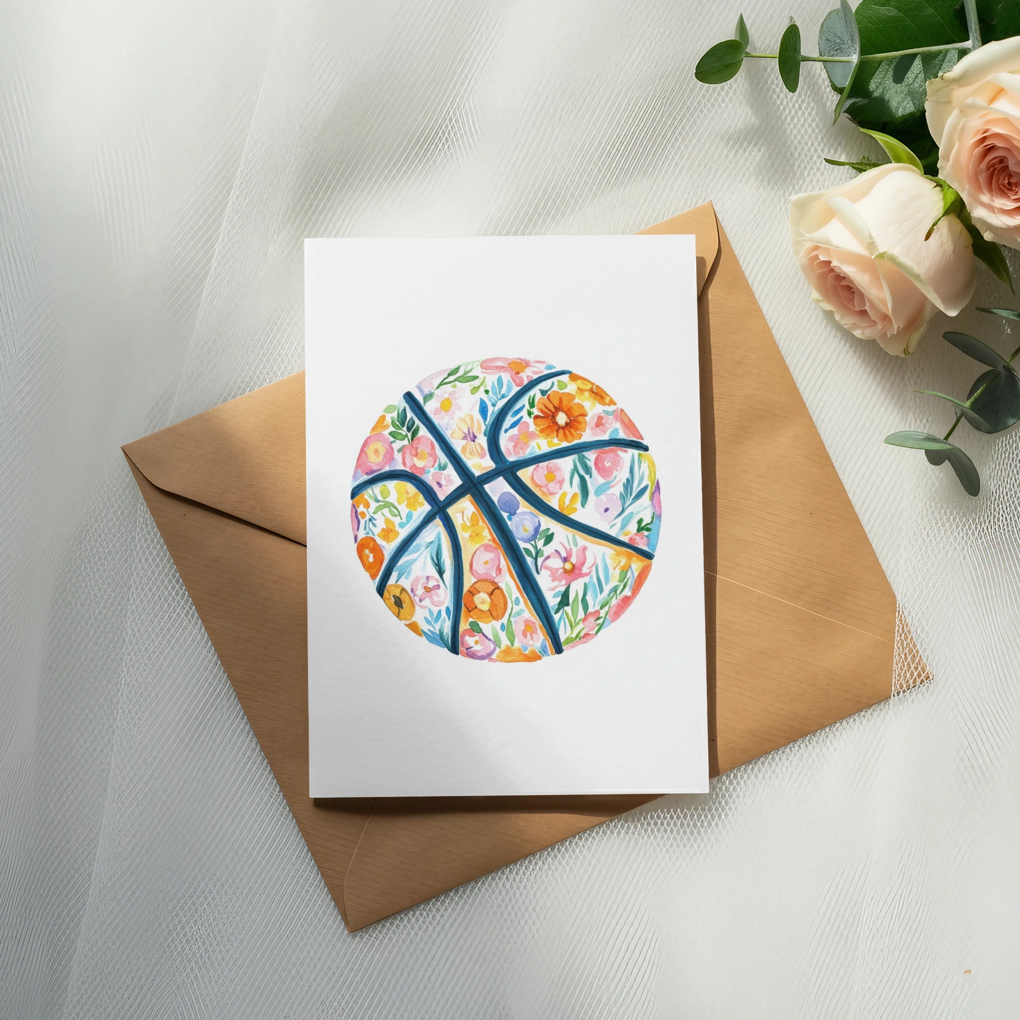 Floral basketball illustration on a card atop a brown envelope and roses.