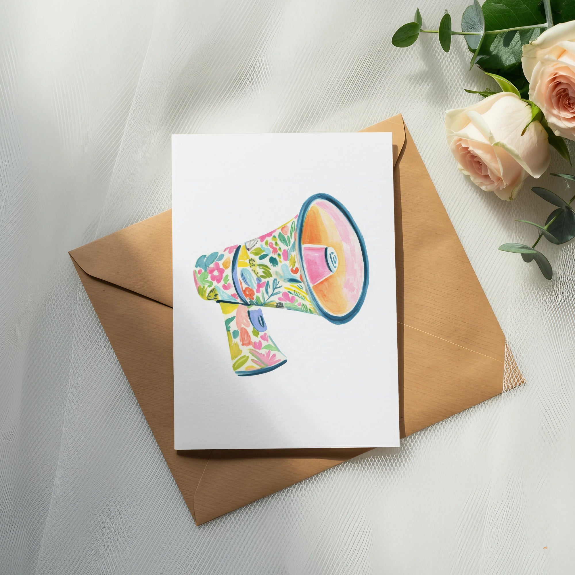 Floral megaphone illustration on card next to envelope and roses.