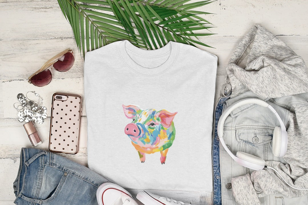 White t-shirt with colorful abstract pig graphic, laid flat with accessories.